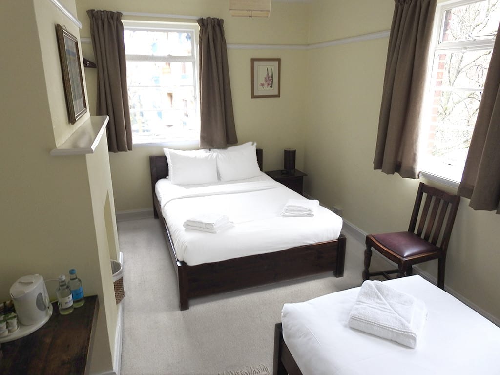 A room with a double bed and single bed plus desk
